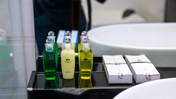 A bathroom counter with three bottles of liquid soap and several boxes of toiletries.