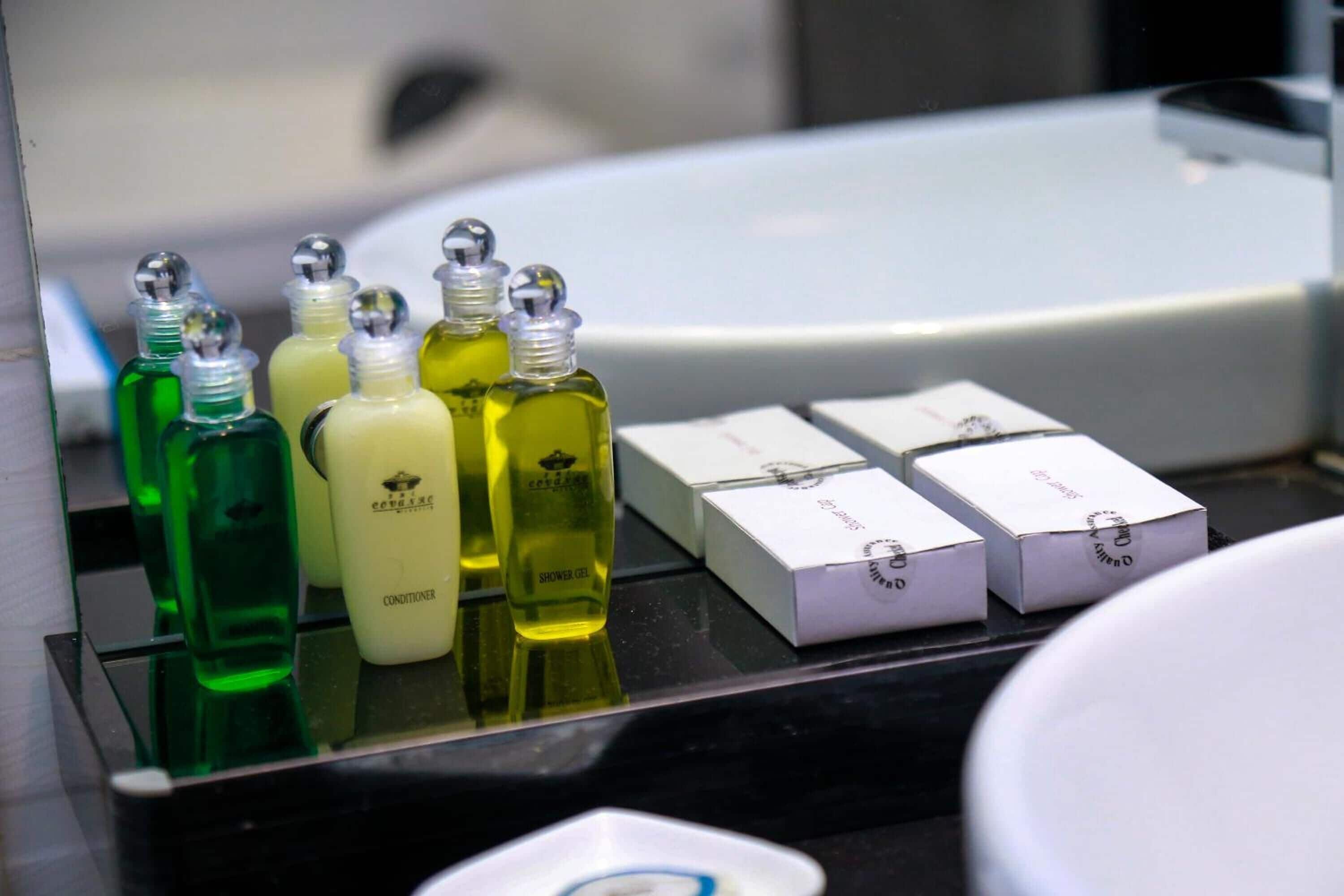 A bathroom counter with various toiletries and a mirror reflecting a bathtub.