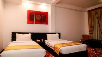 Habitación de hotel con dos camas, alfombra roja, una pared con tres obras de arte rojas y una cortina en la ventana.