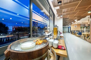 Una mesa de buffet con un barril de madera, platos y un bol de frutas.