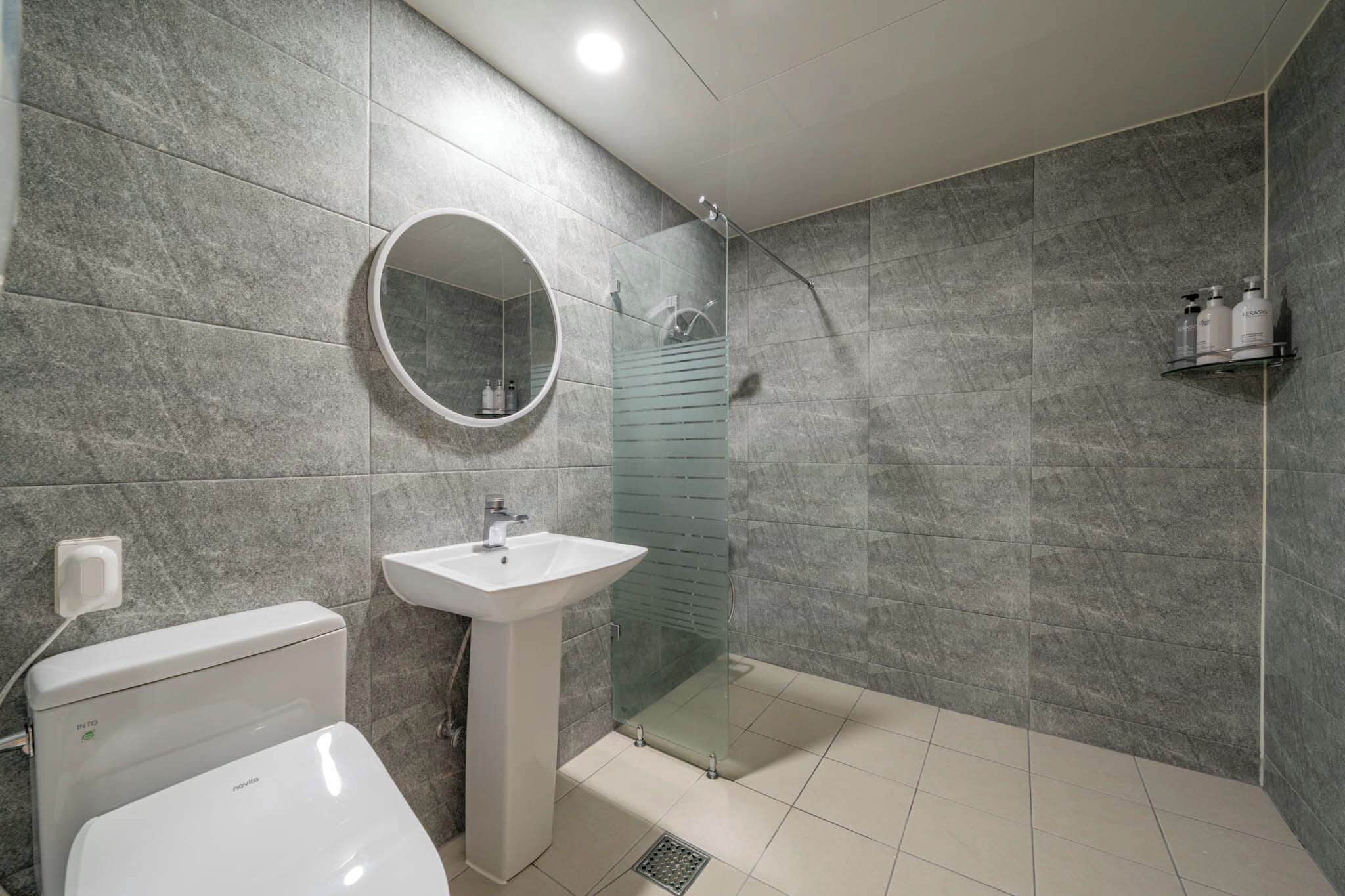 A modern bathroom with a toilet, sink, and glass-enclosed shower.