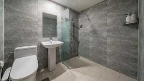 A modern bathroom with a toilet, sink, and glass-enclosed shower. - OST Hotel (Chuncheon)