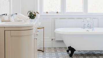 Un baño con una bañera blanca, un lavamanos con espejo y una planta.