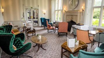 A room with a fireplace, multiple seating areas, and large windows.