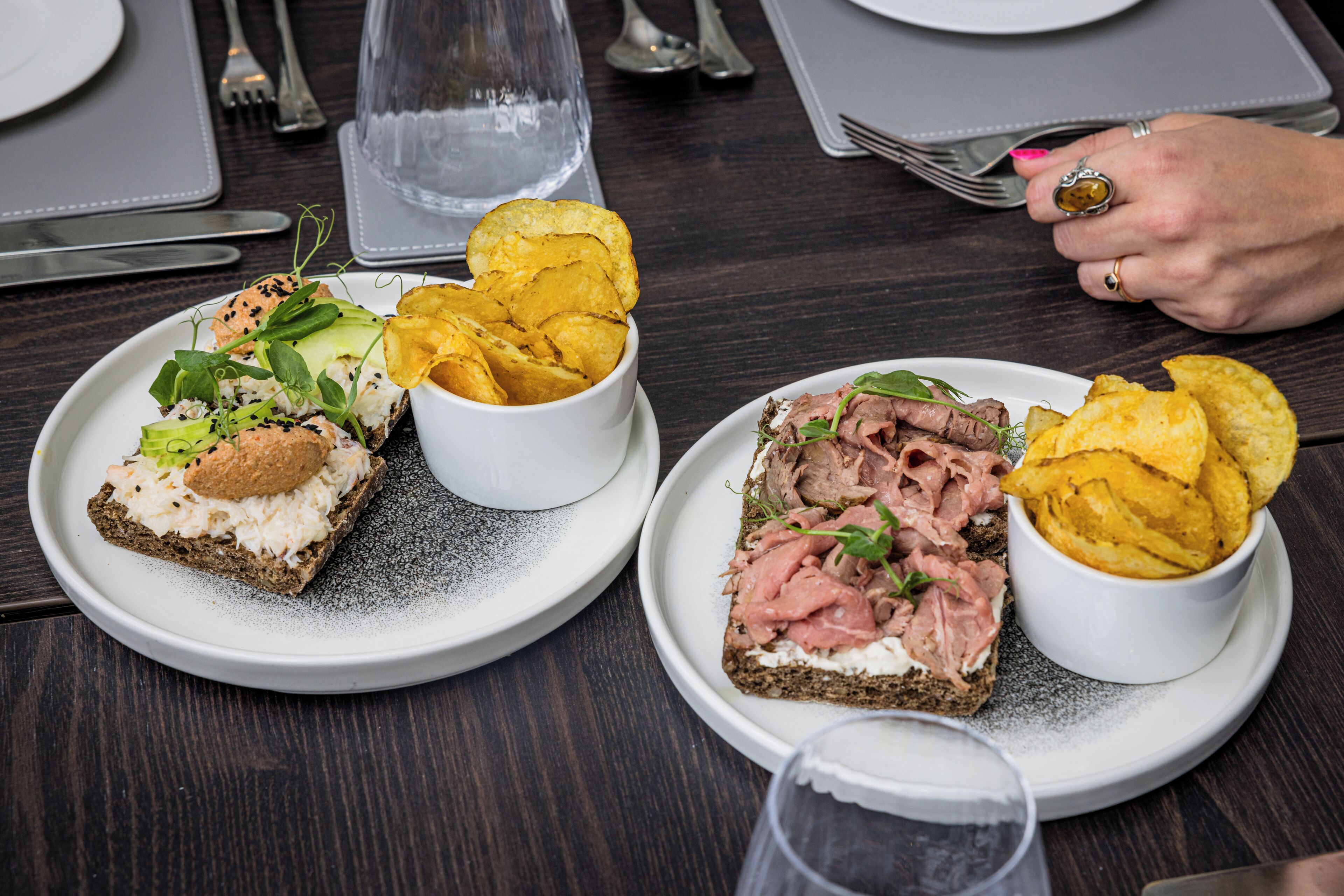 A table with two plates of food, a glass of water, and a fork.