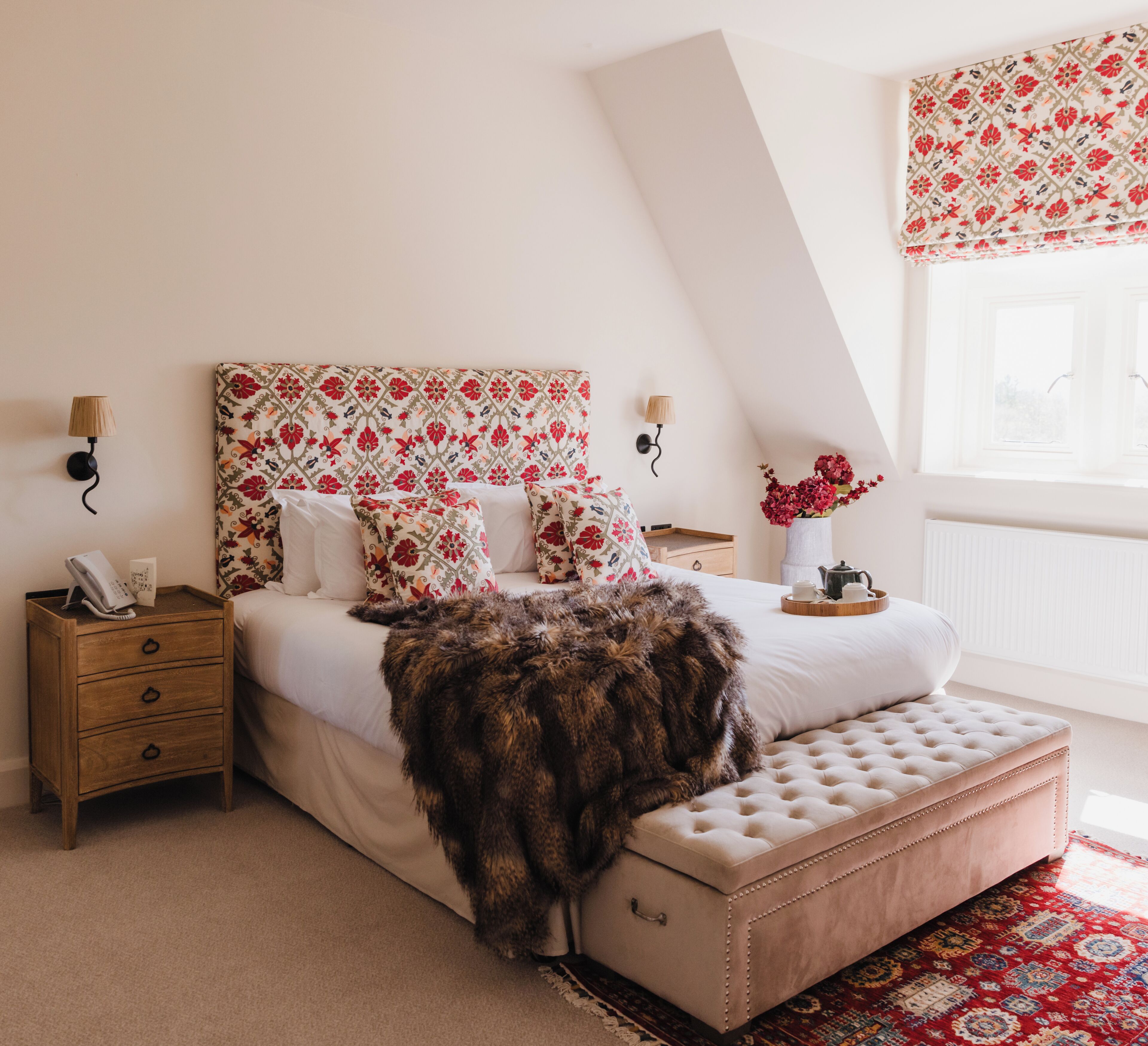 Een slaapkamer met een bed, nachtkastjes, een vloerkleed en een raam met uitzicht.