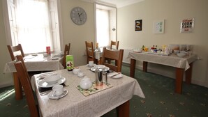 A dining area with two tables, chairs, a clock, and a wall clock. - Inglestone House (Kelso)