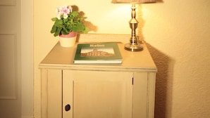 A small bedside table with a lamp, a book, and a potted plant. - Inglestone House (Kelso)