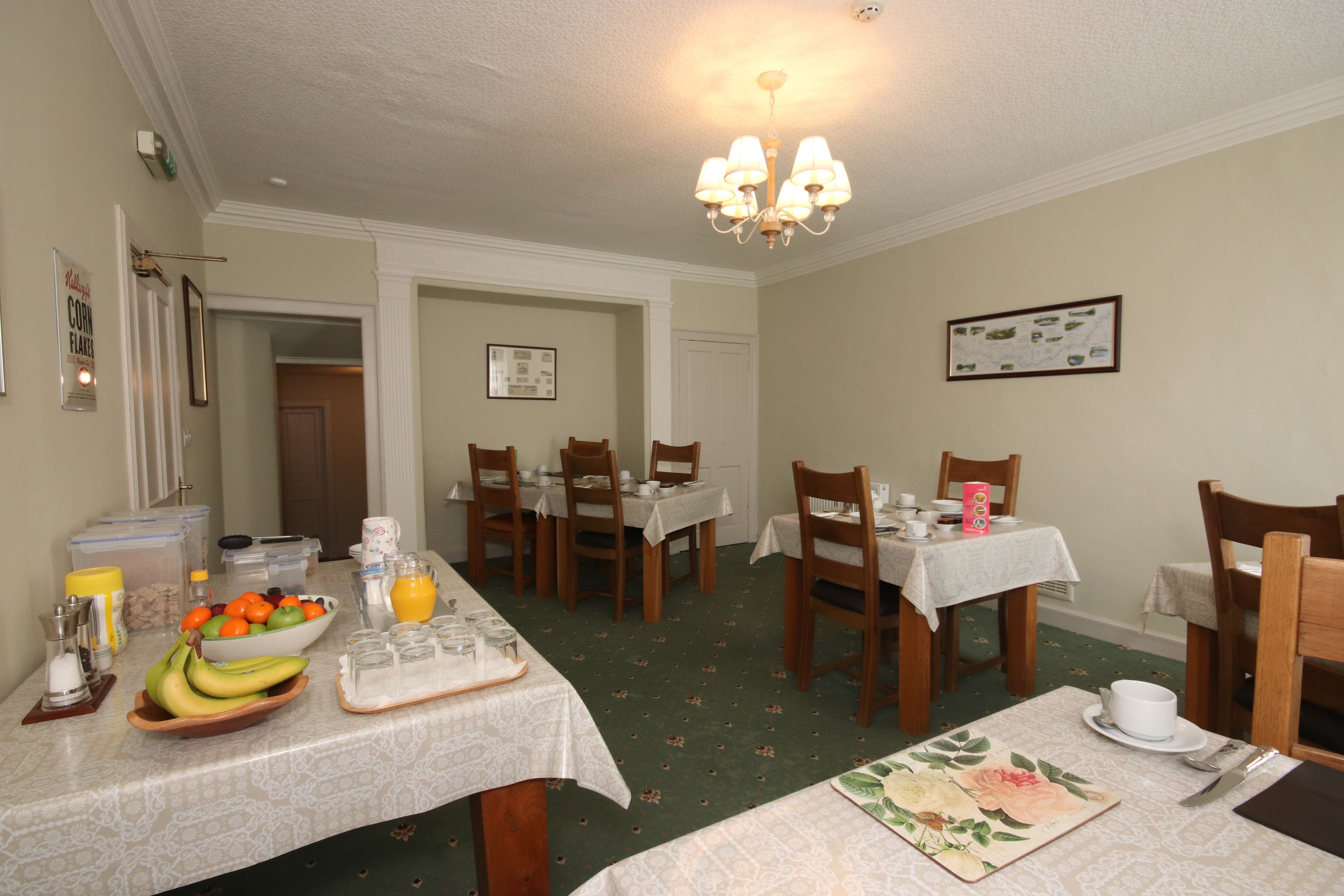 A dining area with tables set for breakfast, including fruits, beverages, and breakfast items.