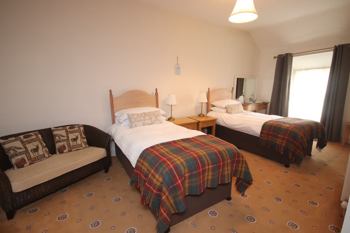 Habitación de hotel con dos camas, un sofá y una pequeña mesa.