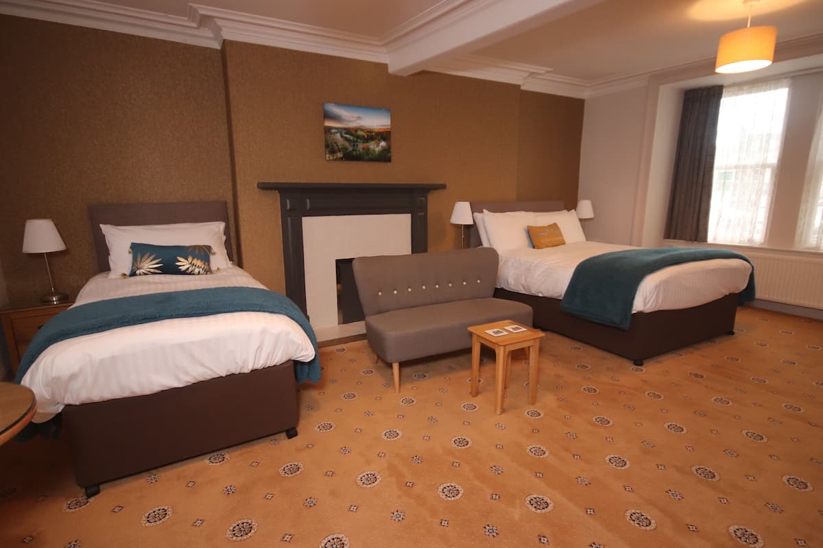 Habitación de hotel con dos camas, un sofá, una mesita y una chimenea.