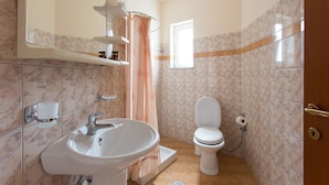 A bathroom with a sink, toilet, and shower curtain. - Hotel Xifoupolis (Monemvasia)