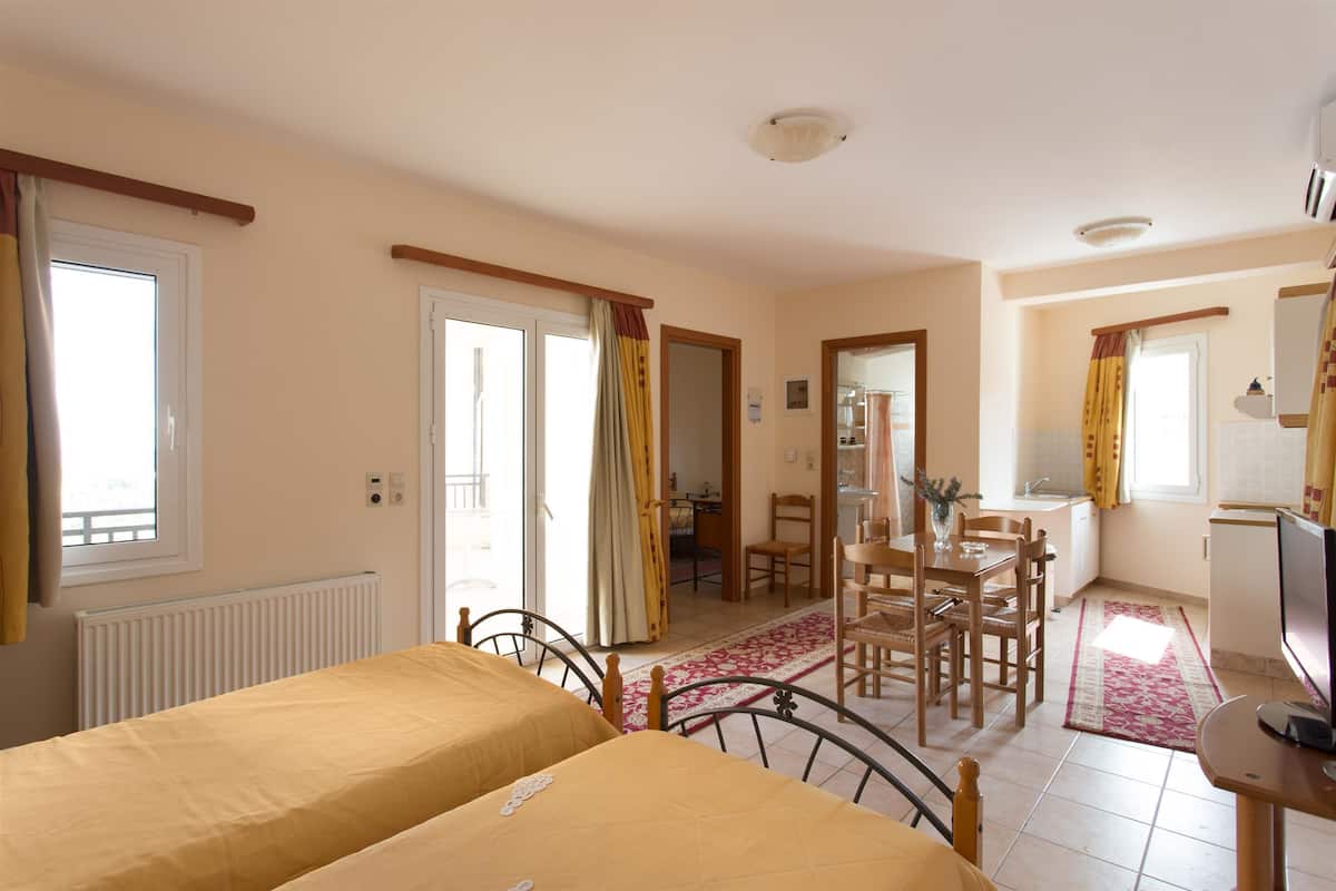 Ein Zimmer mit zwei Betten, einem Esstisch mit Stühlen, einer Küchenzeile und einem Badezimmer.