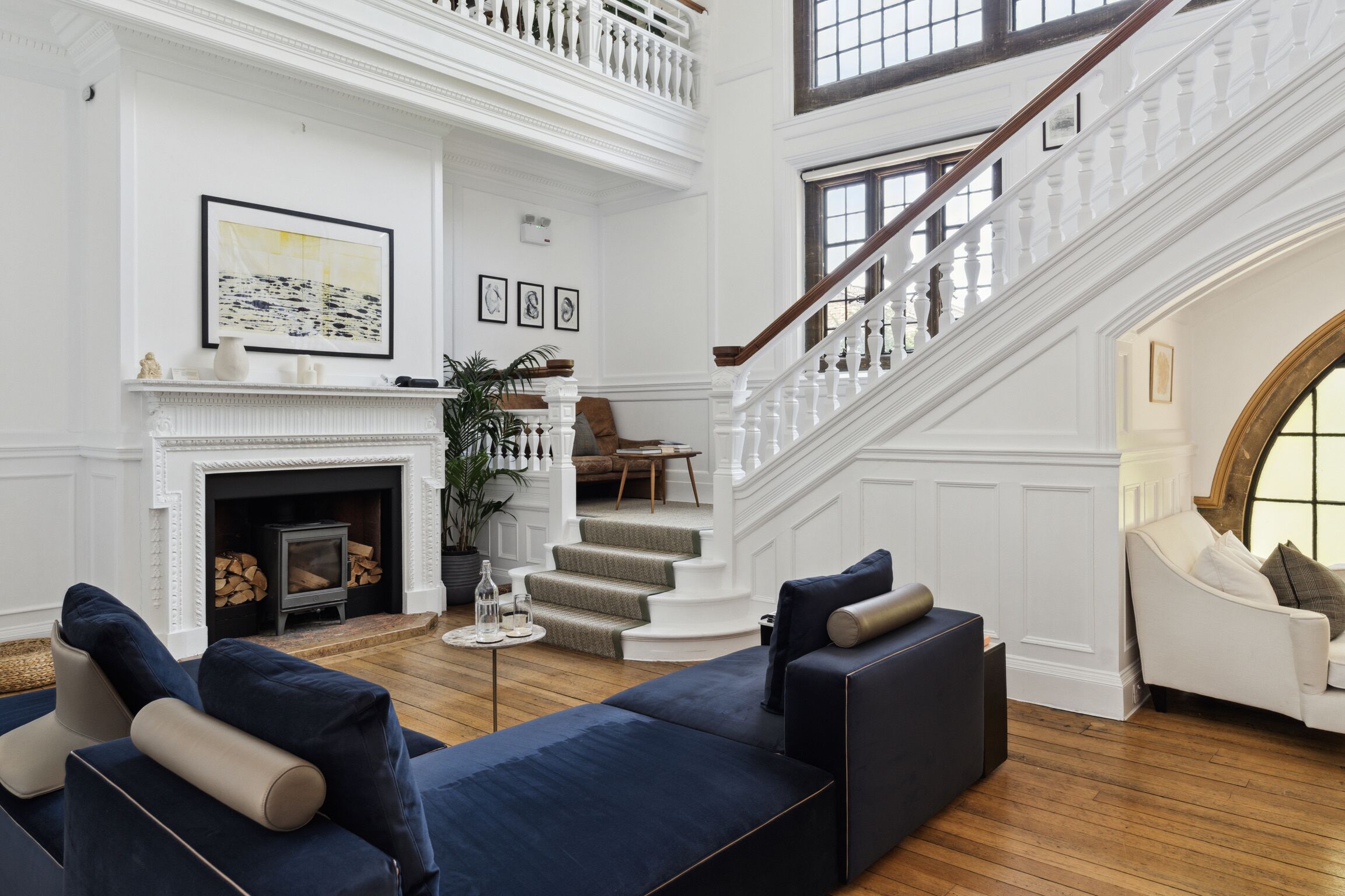 A spacious living room with a fireplace, a staircase, and a large window.