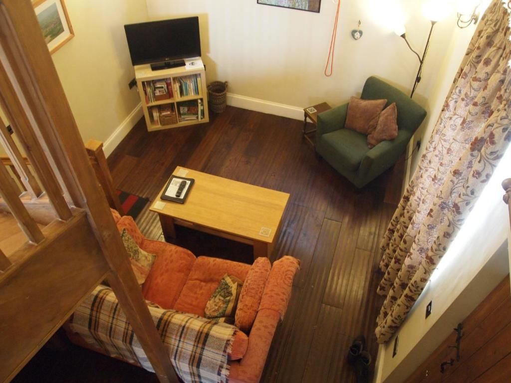 Ein Wohnzimmer mit einer Couch, einem Couchtisch, einem Fernseher und einem Bücherregal.