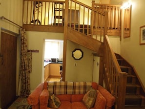A multi-level wooden staircase, a living room with a sofa, and a kitchen area. - The Stables at Owlett Hall (Scunthorpe)