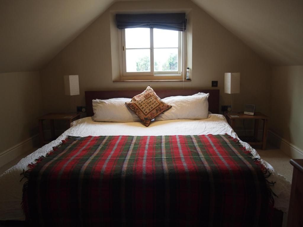 A bedroom with a bed, a window, two bedside tables, and a nightstand.