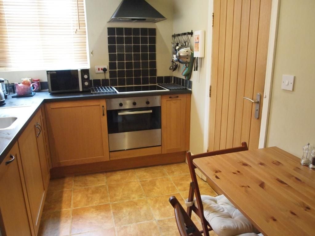 A compact kitchen with a stove, oven, and microwave. There is a wooden table and chairs.