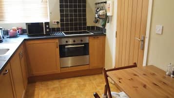 A compact kitchen with a stove, oven, and microwave. There is a wooden table and chairs.