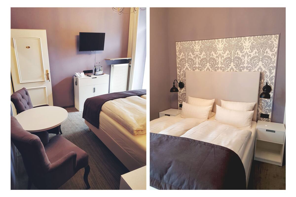 Een hotelkamer met een bed, nachtkastje, lamp en een televisie aan de muur.