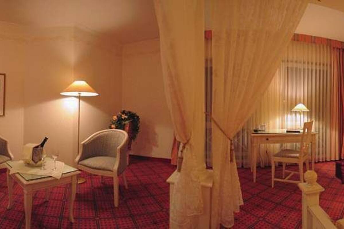 Een hotelkamer met een bed, twee stoelen, een bureau en een nachtkastje.