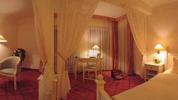 Une chambre d’hôtel avec un lit, deux chaises, un bureau et une table de chevet.