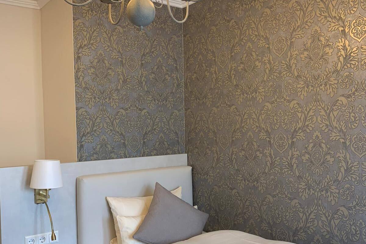 Een slaapkamer met een bed, nachtkastje, lamp en een kroonluchter.