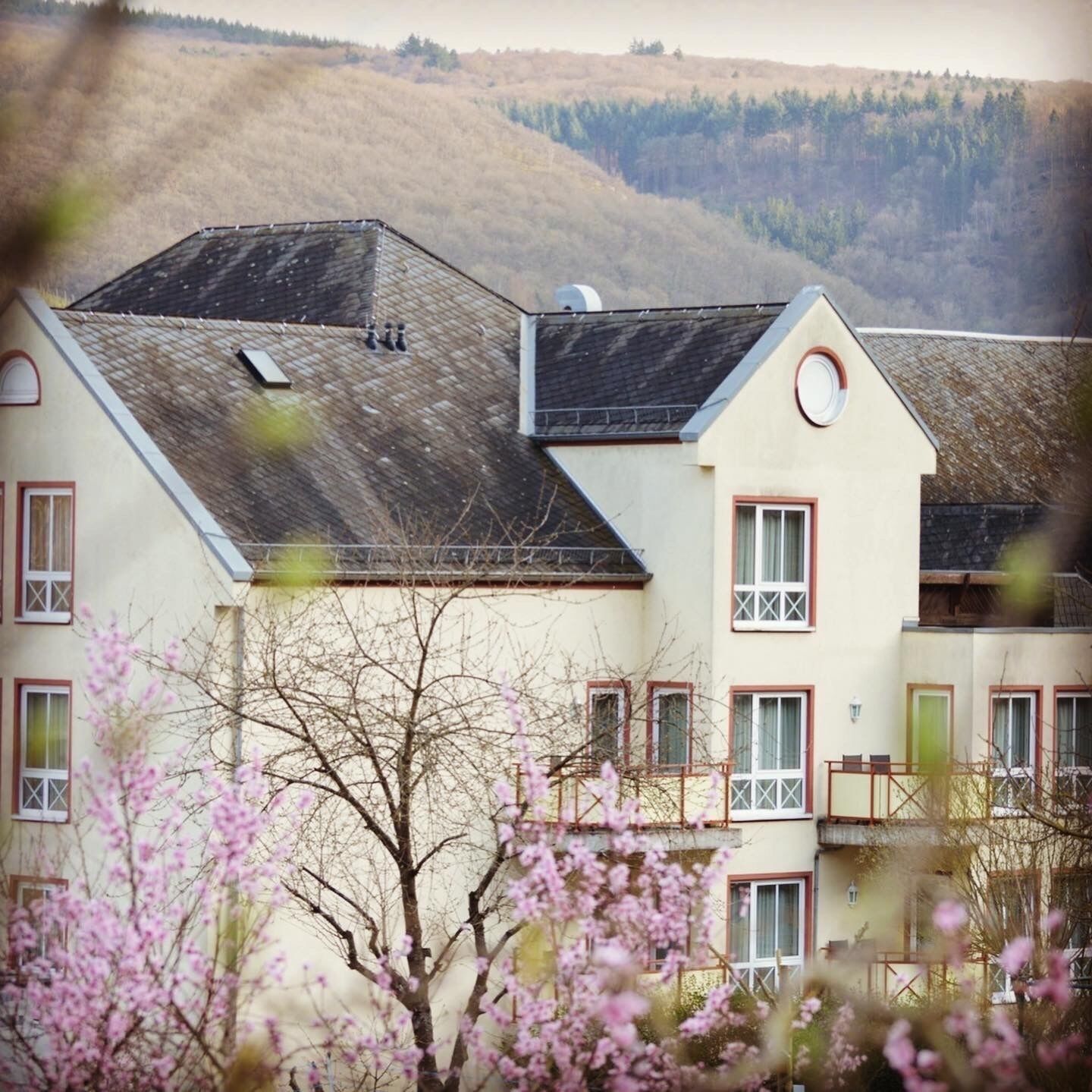 Ein zweistöckiges Gebäude mit geneigtem Dach, zahlreichen Fenstern und einem Balkon.