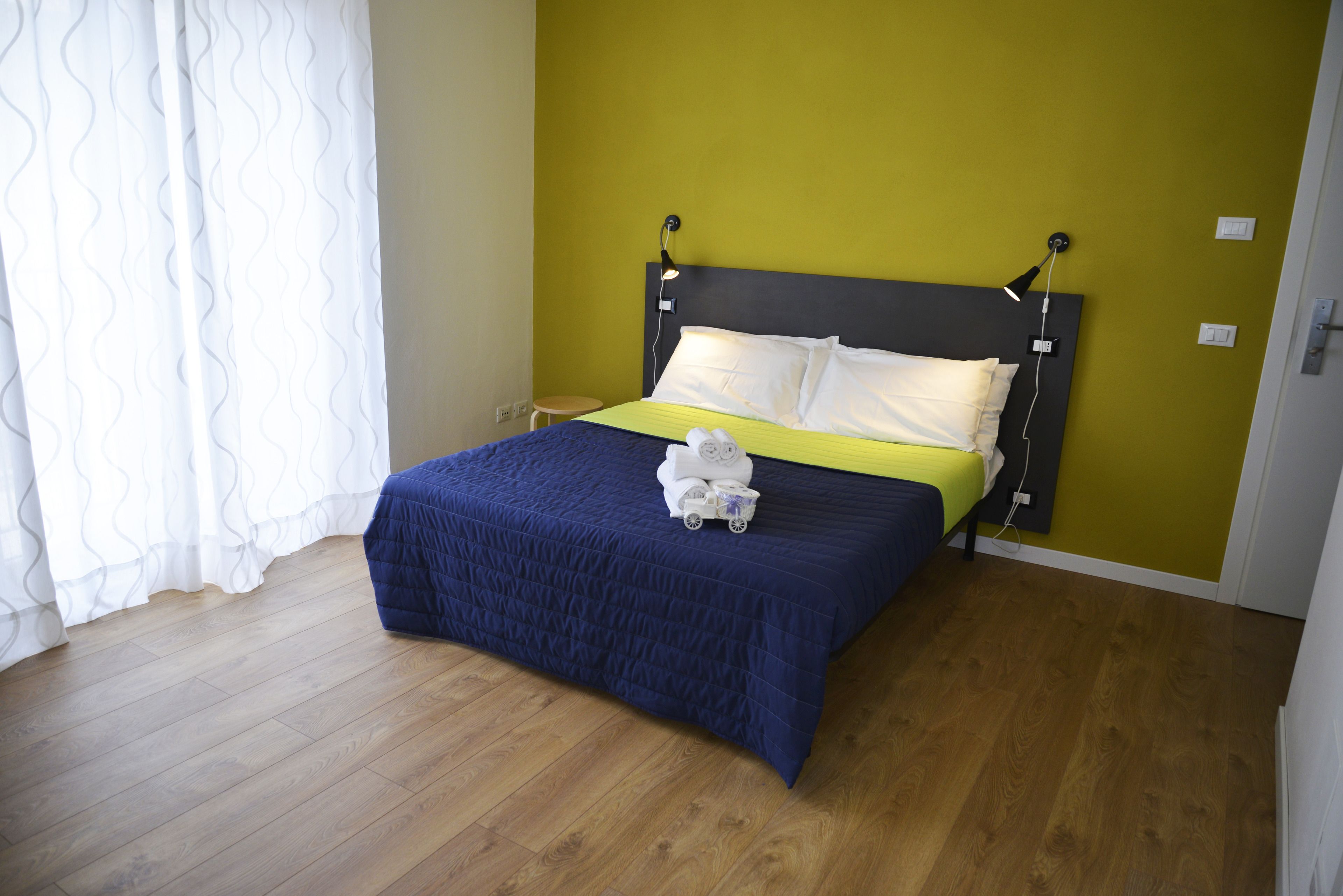 Ein Schlafzimmer mit Holzboden, einem Bett mit blauer Bettdecke, weißen Kissen und einem weißen Handtuch auf dem Bett.