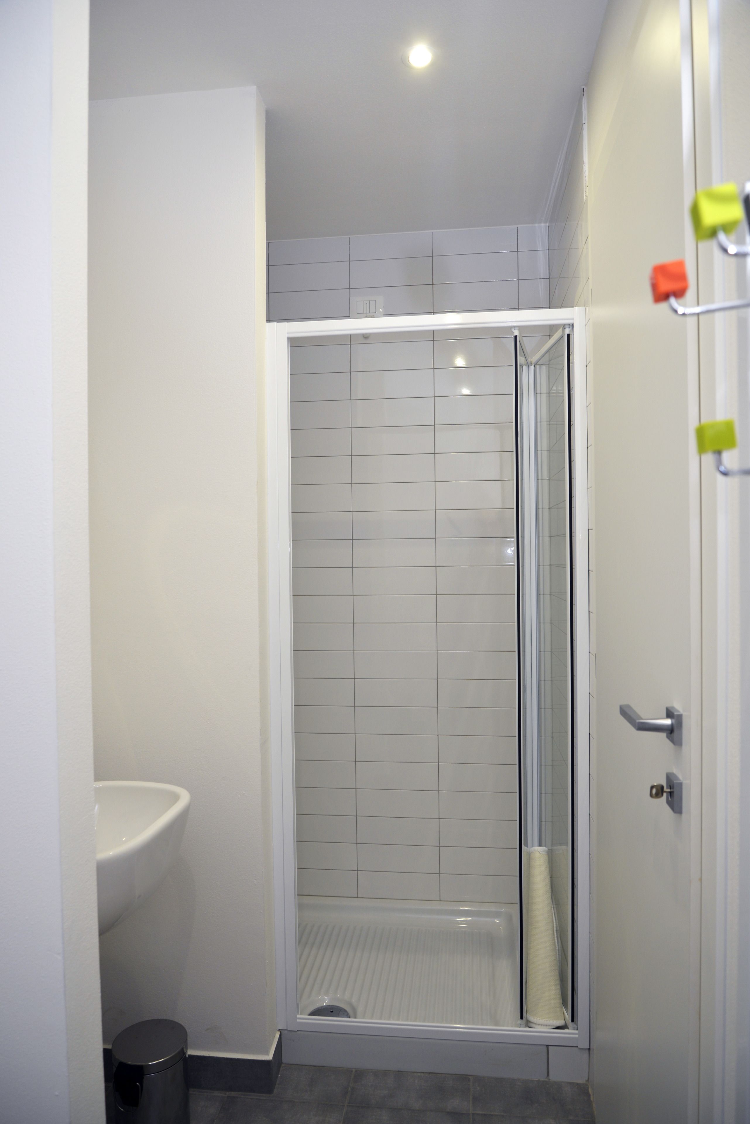 Un baño moderno con ducha envuelta en vidrio, un lavamanos blanco y un inodoro.