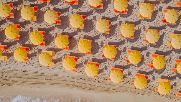 An aerial view of a beach with rows of yellow umbrellas and a sandy shoreline. - Suite 10 - Home, Design & Spa (Polignano a Mare)