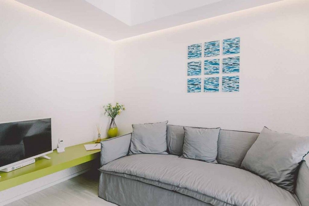 Una sala de estar moderna con un sofá gris, un televisor de pantalla plana y una pared de acento verde.