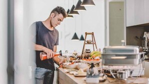 A modern kitchen with a person preparing food, a grill, and various food items on the counter. - Suite 10 - Home, Design & Spa (Polignano a Mare)