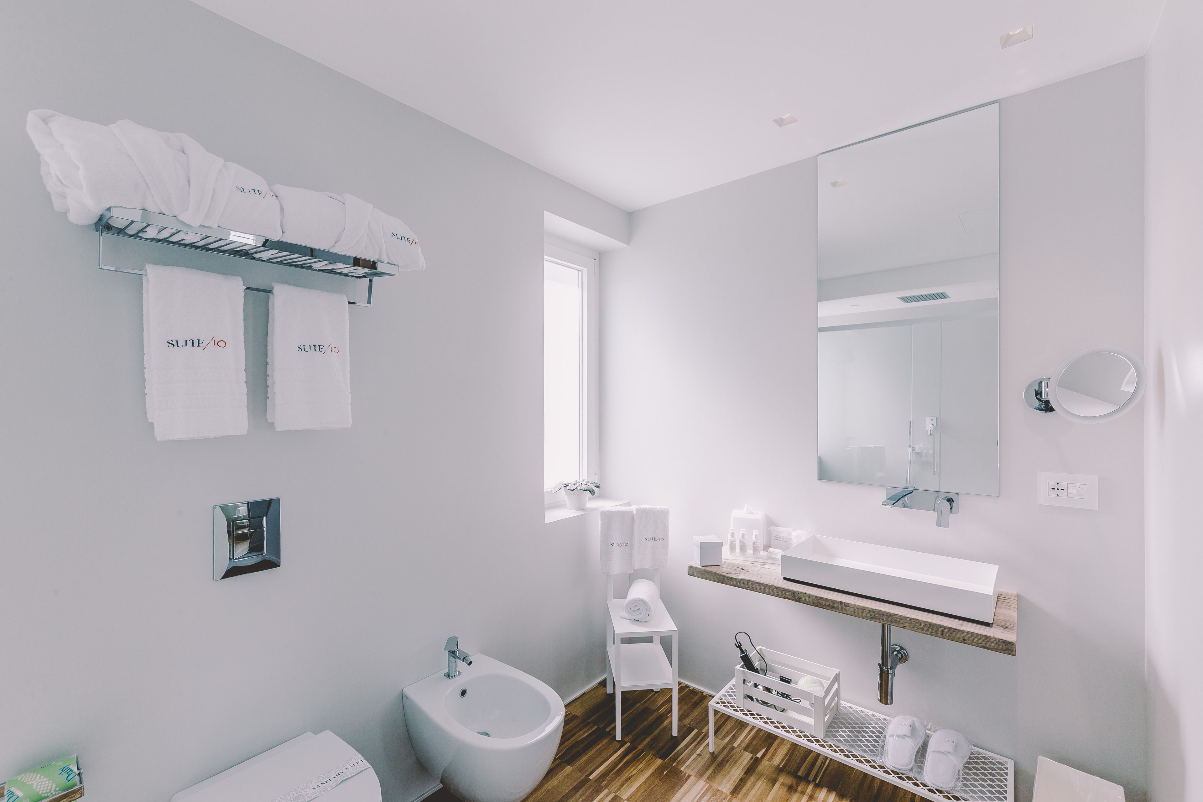 Une salle de bain moderne équipée d’un bidet, d’un lavabo, d’un miroir et de serviettes étiquetées « SUITE/10 ».