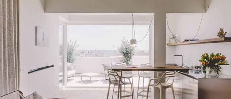 Un espacio moderno de estar con comedor, cocina y balcón con vistas a la ciudad.