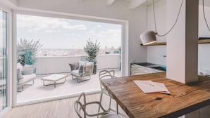 A modern kitchen with a wooden countertop, a hanging pendant light, and a view of the city through large windows. - Suite 10 - Home, Design & Spa (Polignano a Mare)