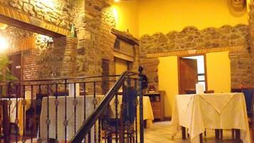 A restaurant with stone walls, a staircase, and tables set for dining.