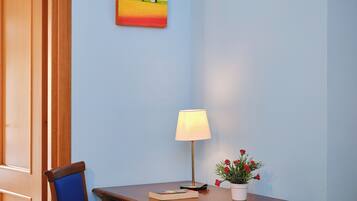 Una mesa de madera con una lámpara, un libro y una maceta con flores rojas.