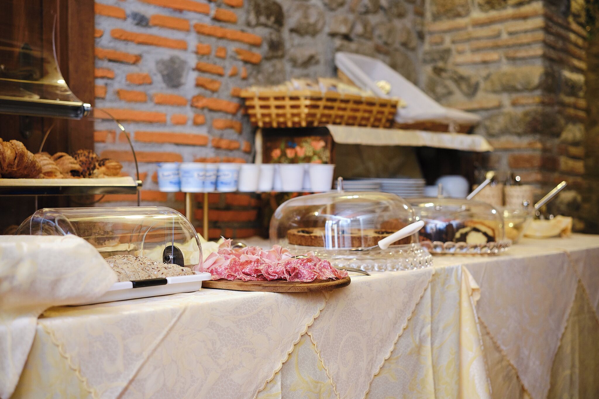 A buffet table with various food items and a brick wall in the background.