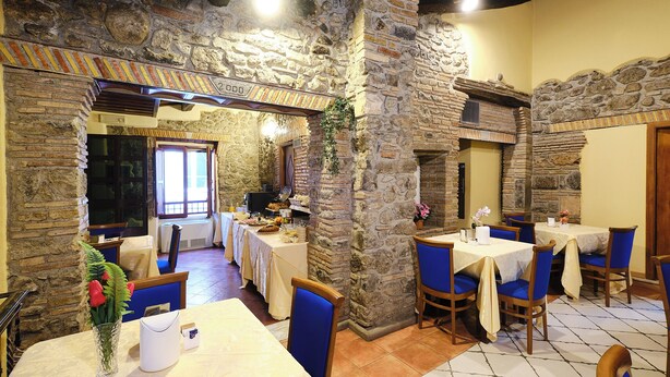 A restaurant with stone walls, blue chairs, and tables set for dining. - Albergo della Posta (Bracciano)