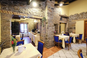Un restaurante con paredes de piedra, sillas azules y mesas dispuestas para comer.