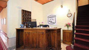 A reception desk with a wooden finish, a wall-mounted clock, and a sign reading "Albergo Della Posta". - Albergo della Posta (Bracciano)