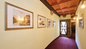 A hallway with framed historical photographs on the wall, a wooden ceiling, and a red carpet. - Albergo della Posta (Bracciano)