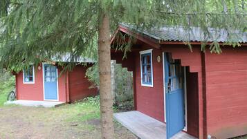 Two red cabins with blue doors and windows, surrounded by trees.