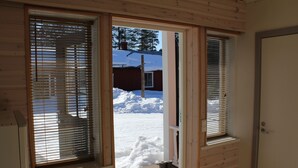 Una cabaña de madera con una puerta que da a un espacio exterior nevado.