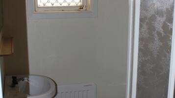 A bathroom with a white sink, a toilet, and a window with a patterned glass door.