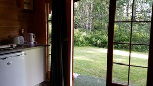 Una cocina con ventana que da a un área verde con árboles.