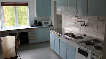 A kitchen with light blue cabinets, a white stove, a sink, and a window with blinds.