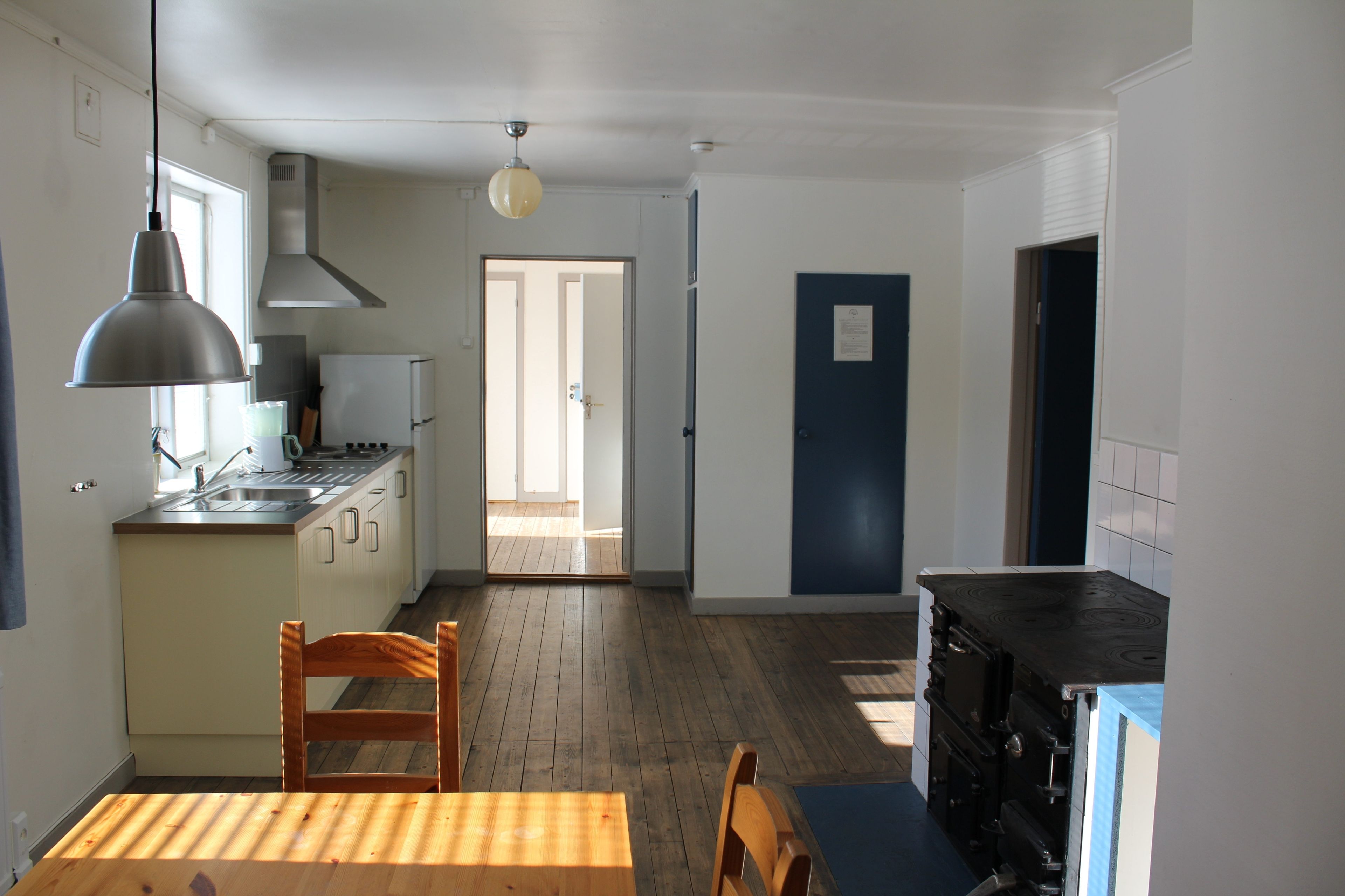 A kitchen with a wooden table and chairs, a stove, and a sink.