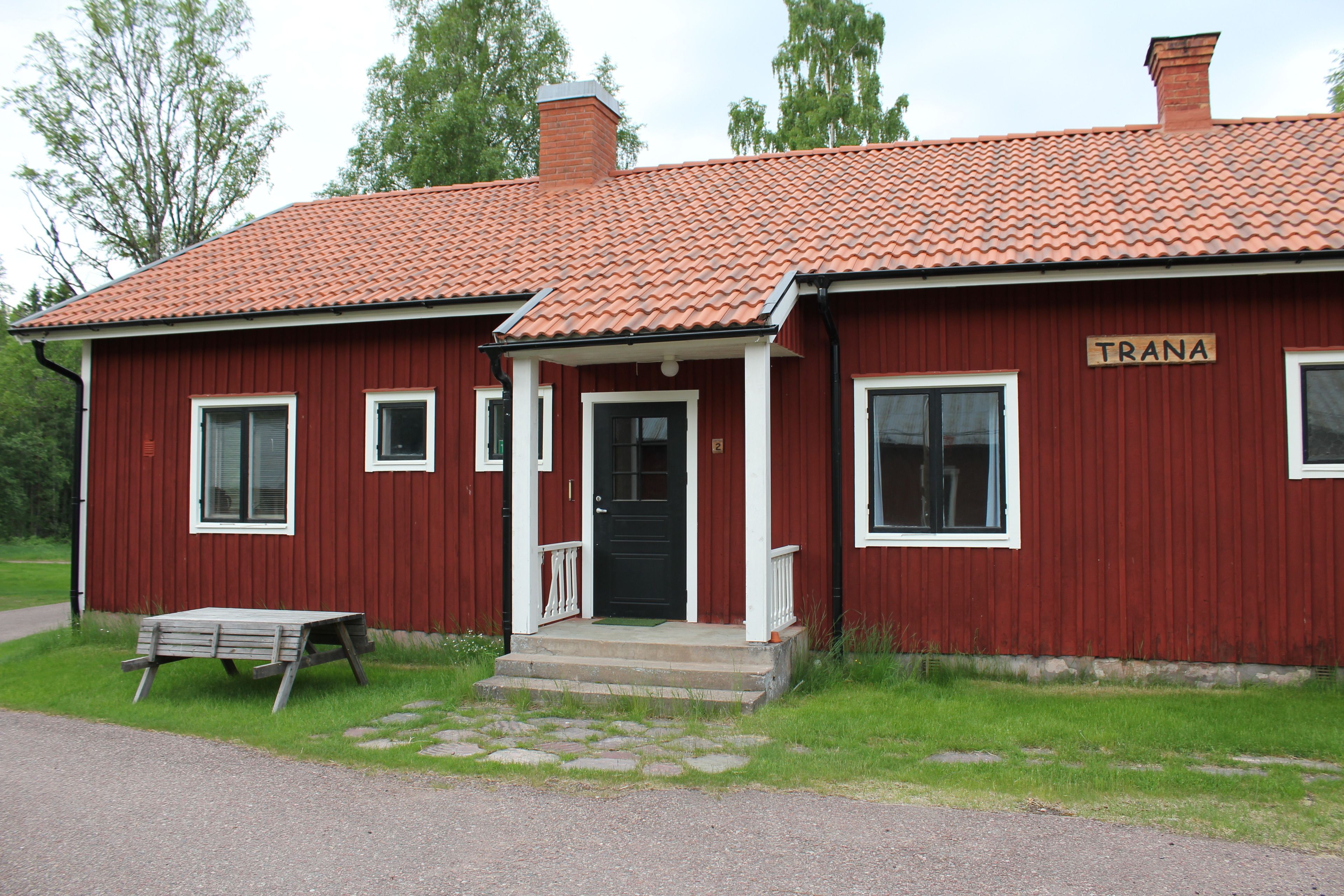 A red building with a tiled roof and a sign that reads "TRANA".